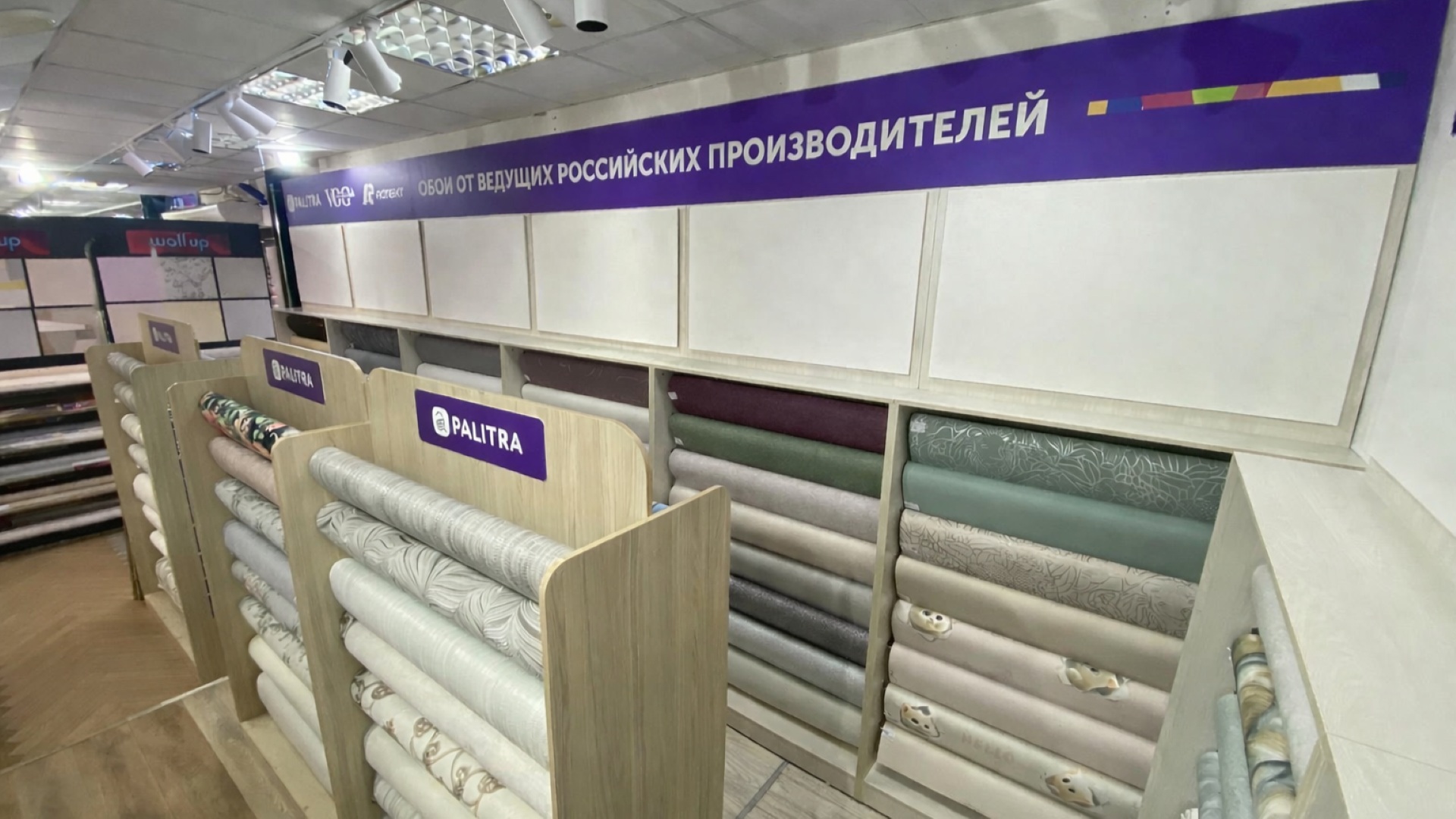 Стеллажи для обоев вдоль стен зала магазина «Палитра» в Твери